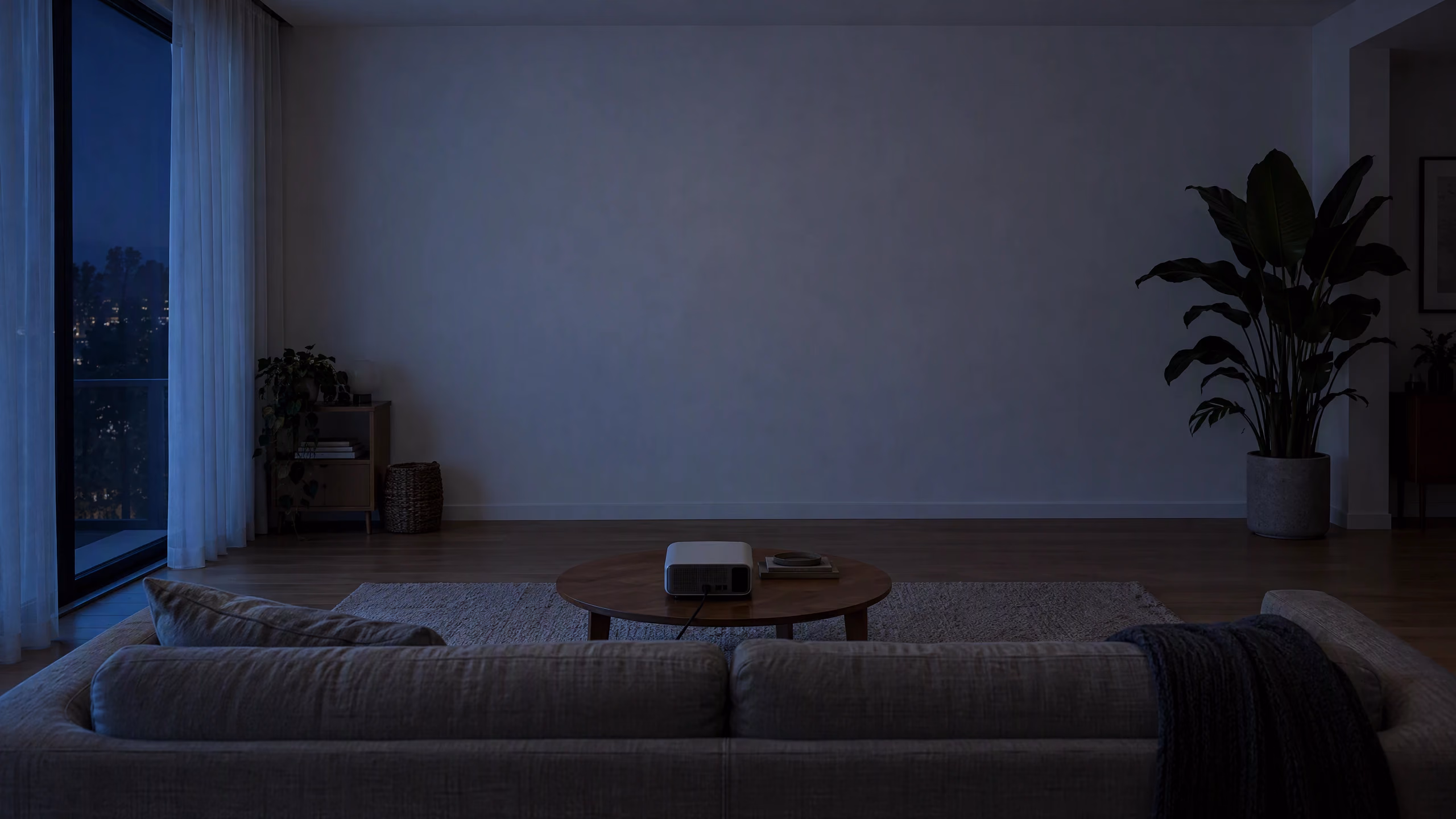 A dim living room with a blank wall and a small projector on the coffee table